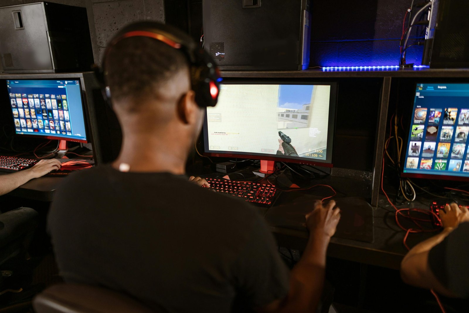 About A man deeply engaged in a video game at a modern esports setup with multiple screens.